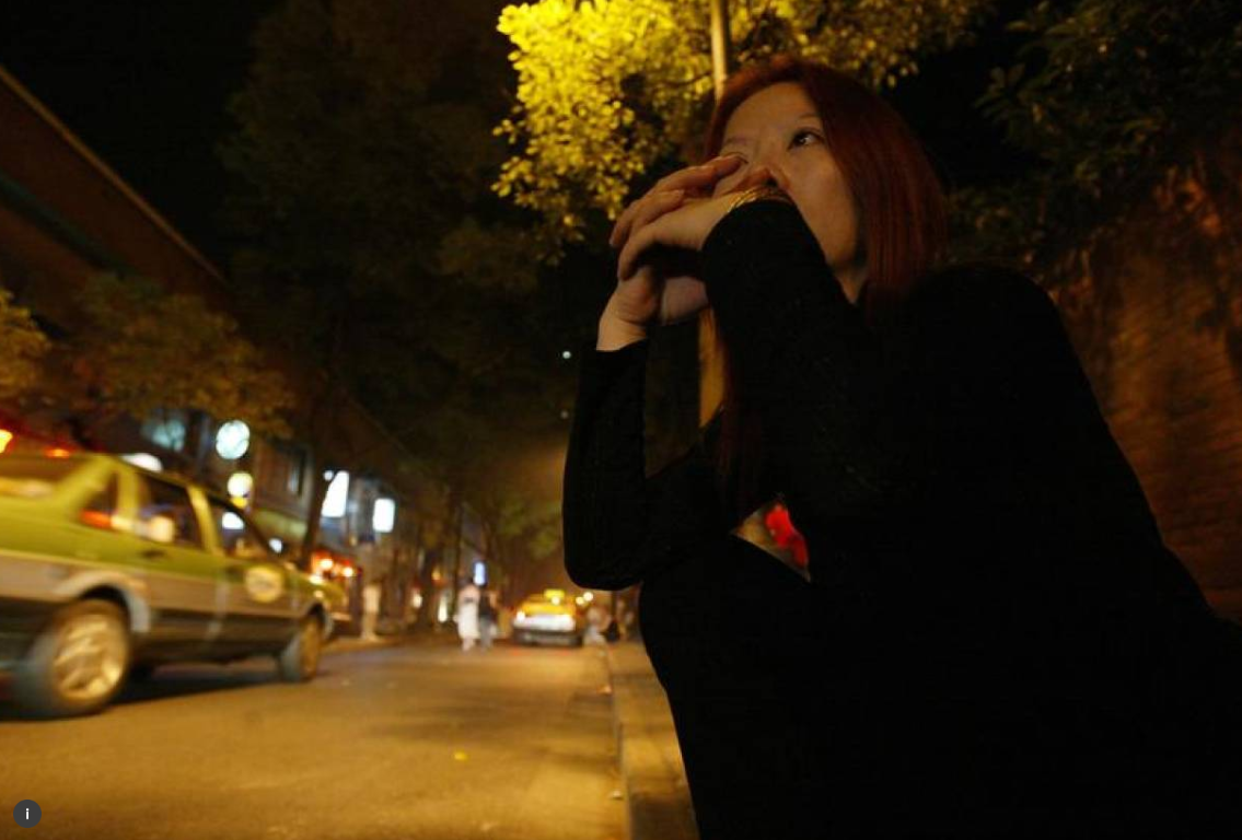 ARCHIVE PHOTO: A prostitute sits in the dark as she waits for customers near a bar district in Shanghai. June, 2003. REUTERS/Claro Cortes IV